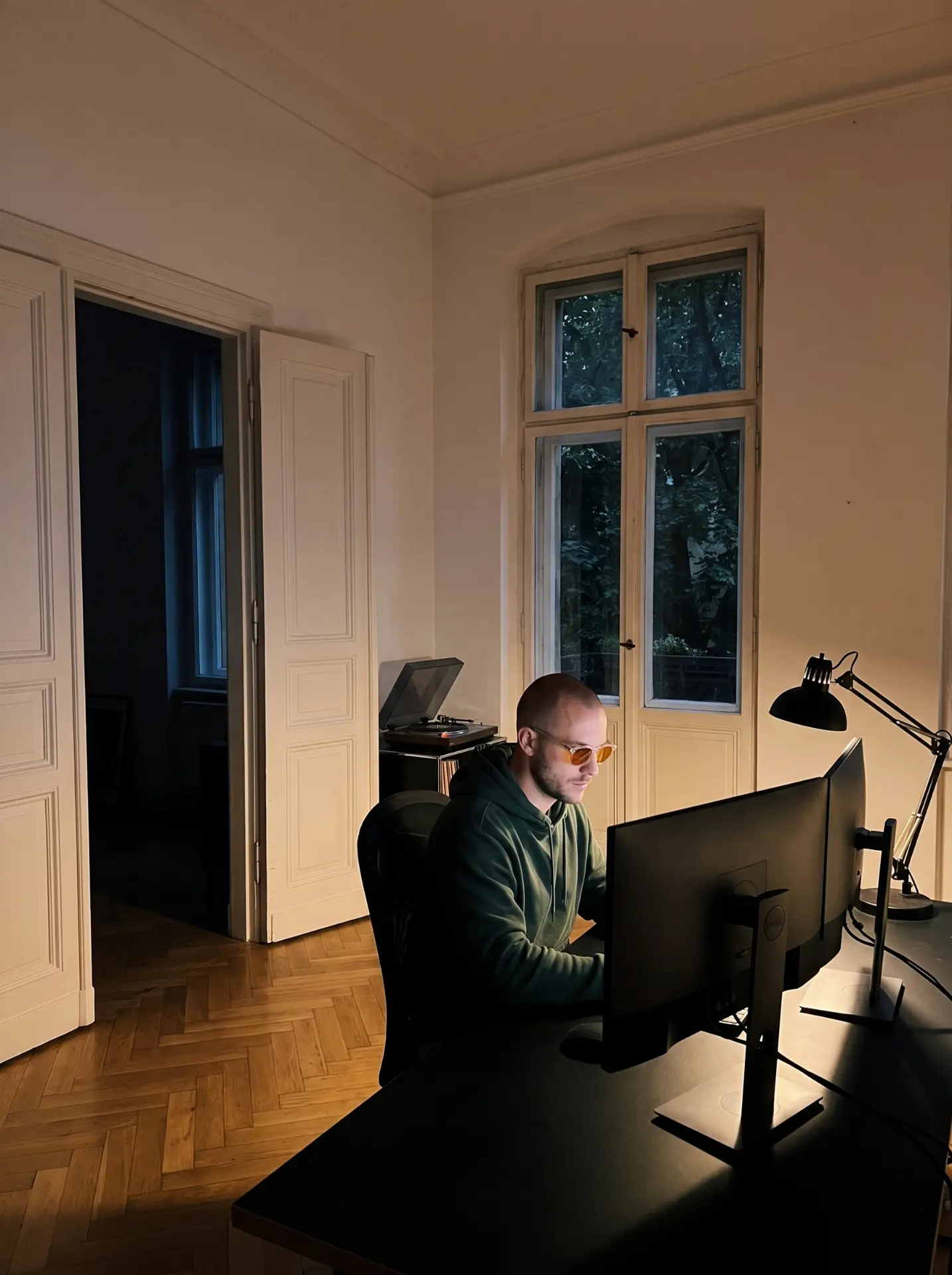 A man in amber glasses working late in a quiet studio